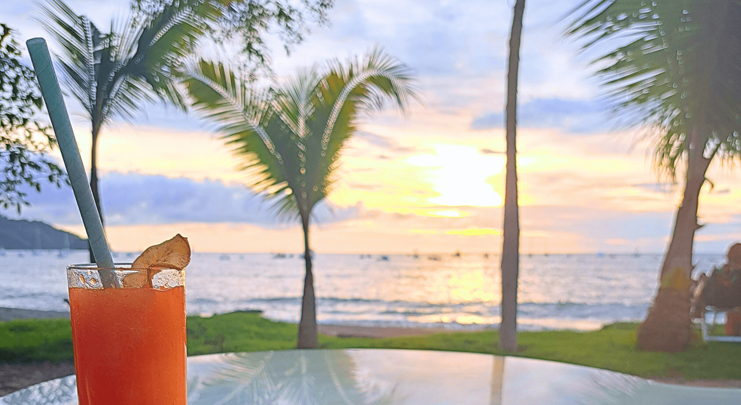 Decorative cover image for desktop webpage. Features a beach at sunset, with an orange drink in the foreground